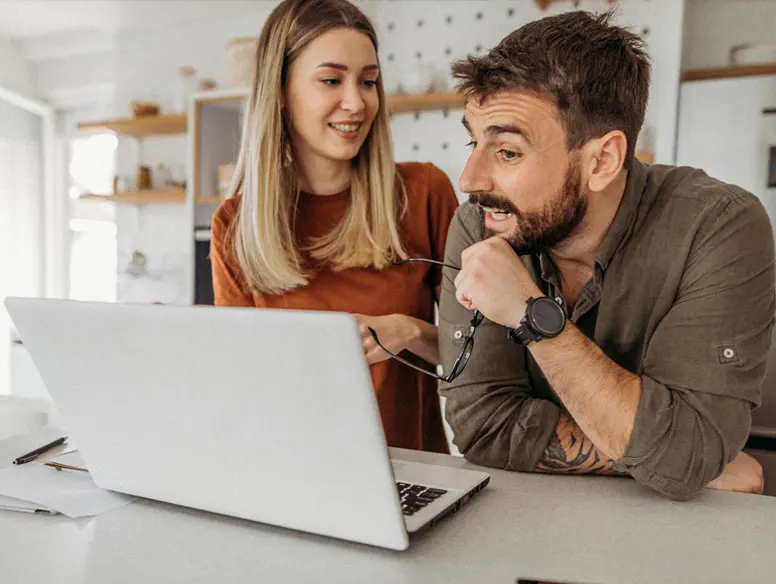 Couple in kitchen looking at laptop