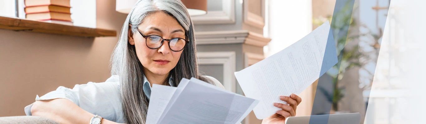 Woman looking over paperwork with laptop