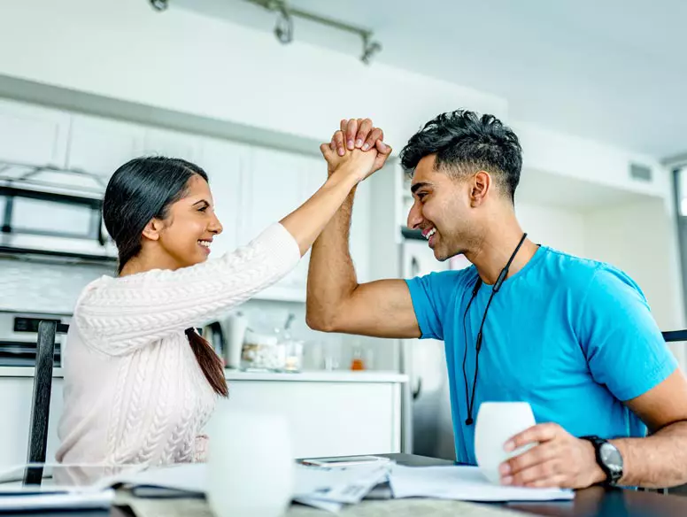 couple in a kitchen celebrating and holding each others hands.