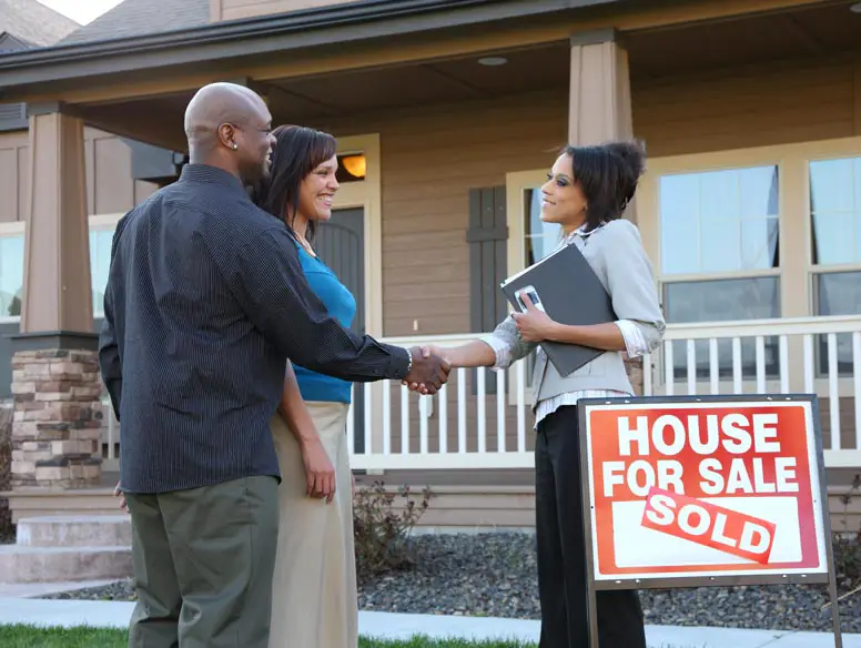 couple shaking hands with real estate agent.