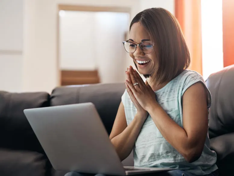Woman smiles while looking at laptop