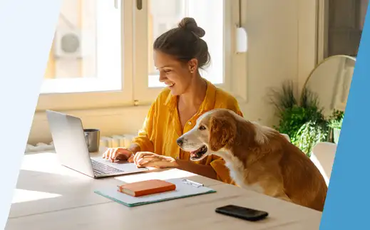 woman using a laptop sitting next to a dog