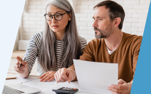 Concerned couple looking at laptop and paperwork