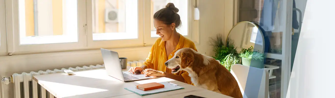 woman using a laptop sitting next to a dog