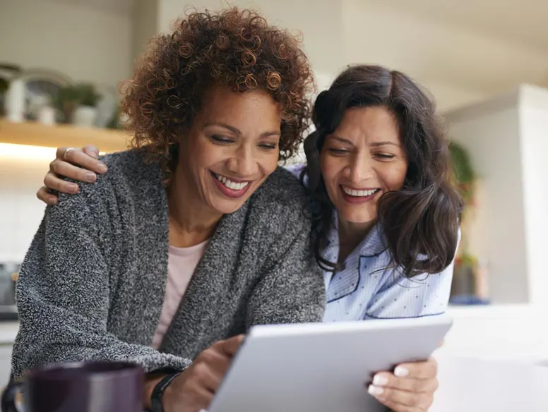 LGBTQ couple looking at mobile tablet in kitchen