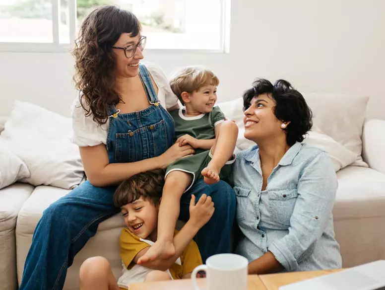 lgbtq couple sitting with children on the couch.