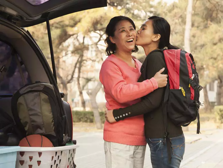 Asian daughter kissing mother goodbye as she leaves for college
