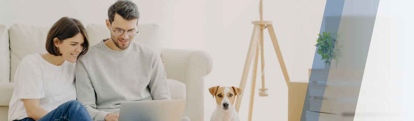 couple seated on floor with dog and laptop